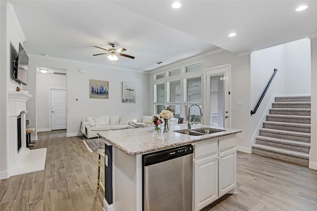 kitchen featuring a fireplace with raised hearth, ornamental molding, open floor plan, stainless steel dishwasher, and a sink