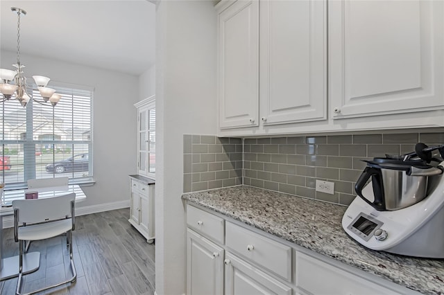 kitchen featuring a chandelier, backsplash, light wood-style flooring, and white cabinets