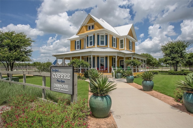 view of front facade featuring metal roof, a porch, and a front lawn