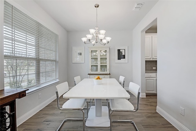 dining area featuring a chandelier, visible vents, dark wood finished floors, and baseboards