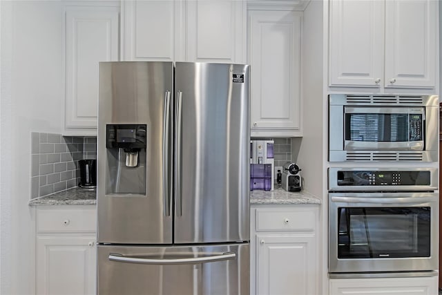 kitchen with appliances with stainless steel finishes, backsplash, light stone counters, and white cabinets