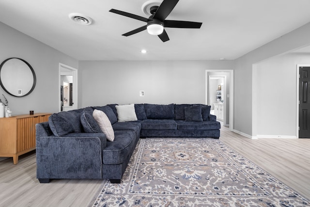 living area featuring ceiling fan, light wood-type flooring, visible vents, and baseboards