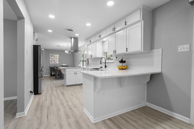 kitchen featuring tasteful backsplash, freestanding refrigerator, a sink, a peninsula, and extractor fan