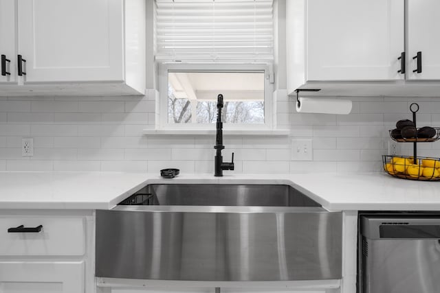 kitchen featuring decorative backsplash, white cabinetry, a sink, and dishwasher