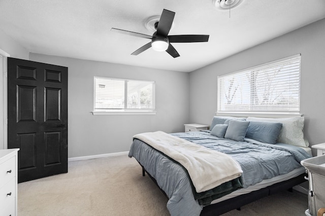 bedroom with light colored carpet, ceiling fan, and baseboards