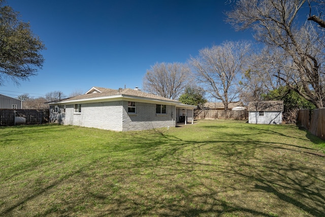 back of house with a yard, a fenced backyard, a storage unit, and an outbuilding