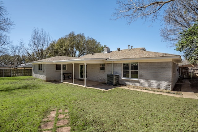 back of property with a yard, a chimney, a patio, central air condition unit, and fence