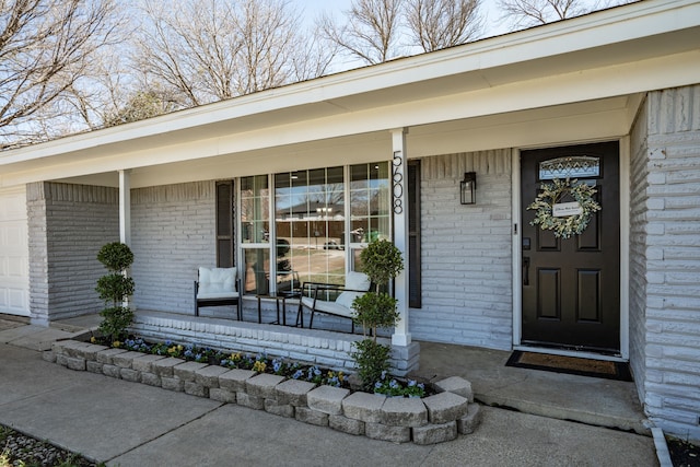 entrance to property with an attached garage, a porch, and brick siding