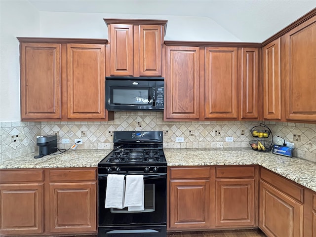 kitchen featuring light stone counters, brown cabinetry, decorative backsplash, and black appliances