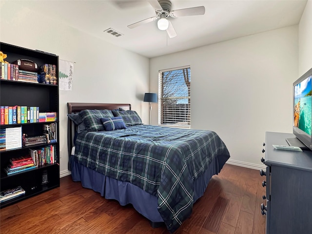 bedroom featuring a ceiling fan, visible vents, baseboards, and wood finished floors