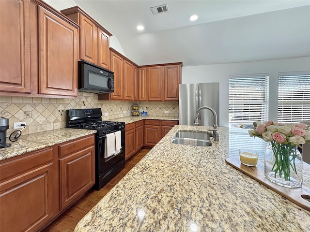 kitchen with light stone counters, tasteful backsplash, visible vents, a sink, and black appliances