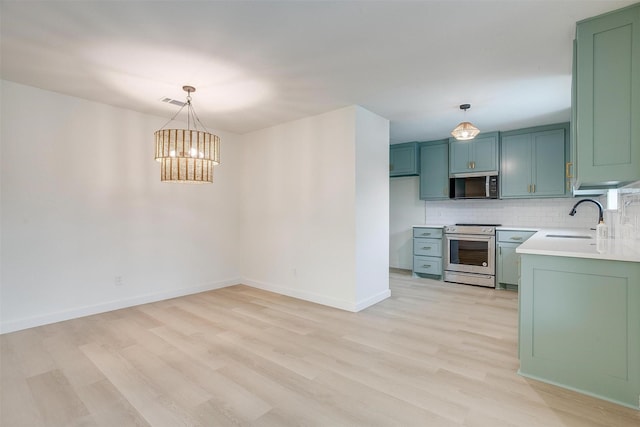 kitchen with decorative backsplash, stainless steel appliances, light countertops, light wood-style floors, and a sink