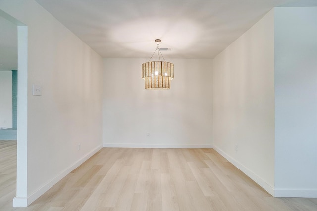 unfurnished room with light wood finished floors, visible vents, baseboards, and a notable chandelier