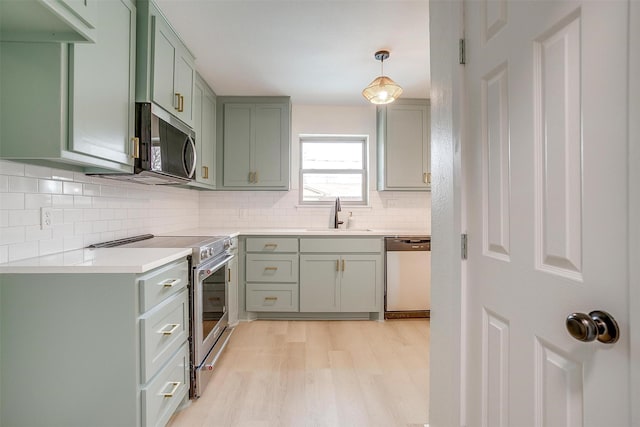 kitchen featuring stainless steel appliances, light countertops, a sink, and green cabinets