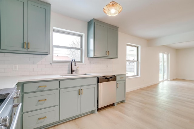 kitchen featuring stove, backsplash, stainless steel dishwasher, light wood-style floors, and a sink