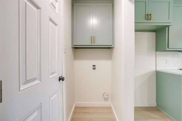 clothes washing area featuring light wood-type flooring, cabinet space, baseboards, and hookup for an electric dryer