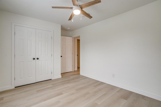 unfurnished bedroom featuring ceiling fan, a closet, light wood-type flooring, and baseboards