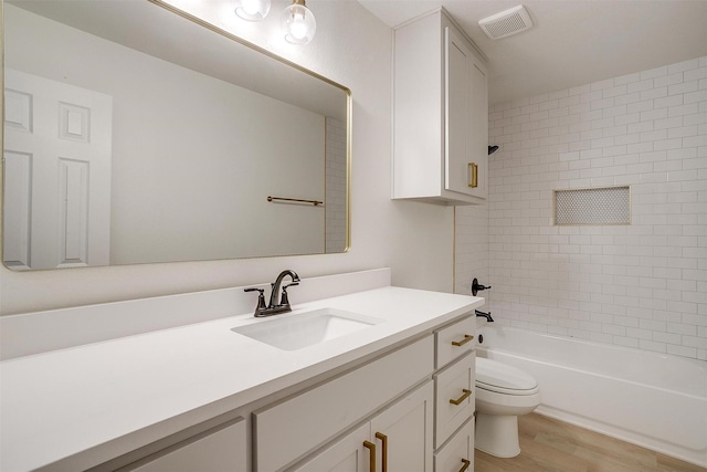 bathroom with toilet, wood finished floors, visible vents, vanity, and bathing tub / shower combination