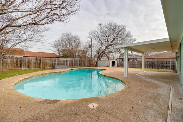 view of pool with an outbuilding, a fenced backyard, a fenced in pool, a shed, and a patio area