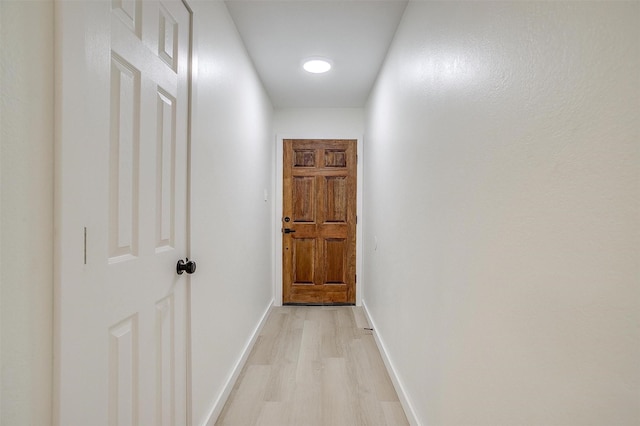 hall featuring light wood-style flooring and baseboards