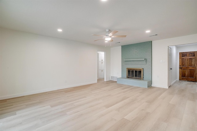 unfurnished living room featuring light wood-style flooring, a fireplace, a ceiling fan, visible vents, and baseboards