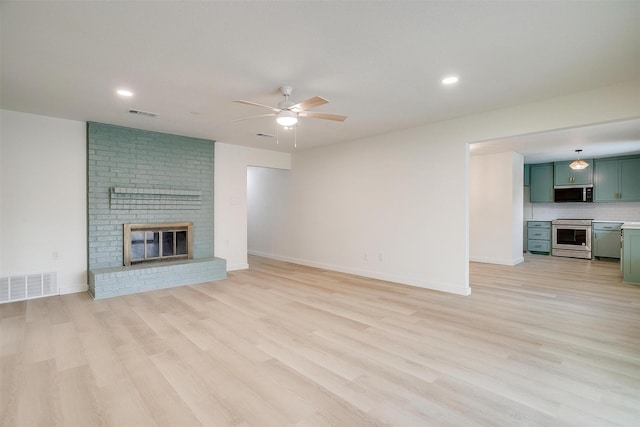 unfurnished living room featuring ceiling fan, light wood-type flooring, a fireplace, and visible vents