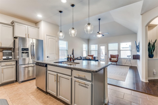 kitchen with stone countertops, stainless steel appliances, gray cabinetry, and a sink