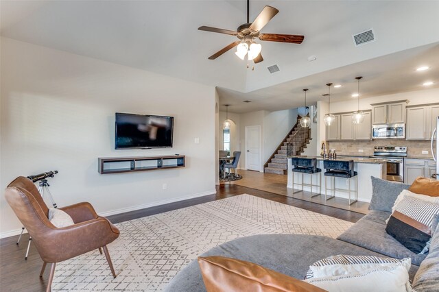 living area featuring ceiling fan, baseboards, arched walkways, wood finished floors, and high vaulted ceiling