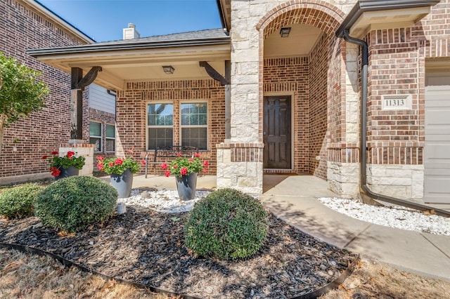 property entrance featuring brick siding, a porch, and an attached garage