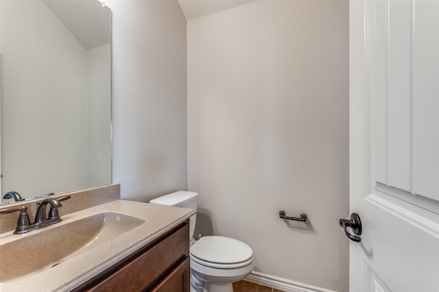 half bath featuring toilet, vanity, and baseboards