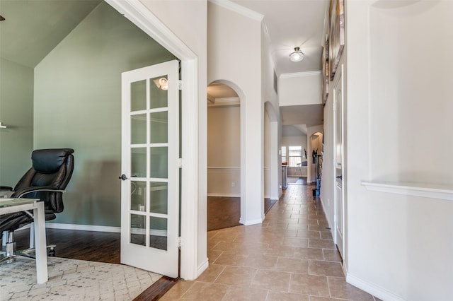 office space featuring french doors, baseboards, ornamental molding, and arched walkways