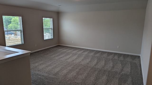 spare room with dark carpet and baseboards