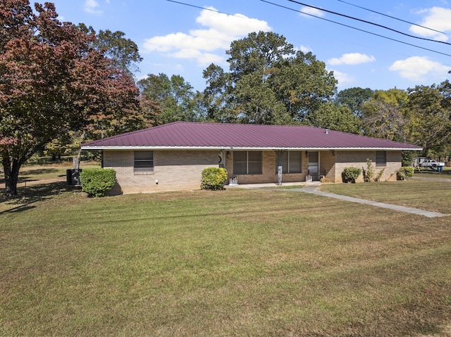 ranch-style home featuring metal roof, a front lawn, and brick siding