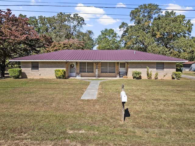 single story home with metal roof, a front lawn, and brick siding