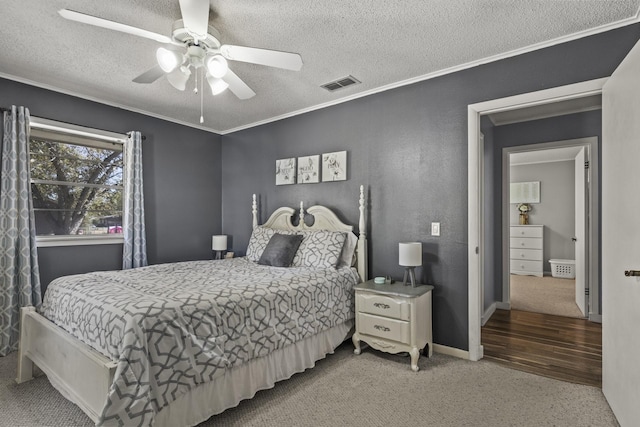 carpeted bedroom featuring ornamental molding, visible vents, a textured ceiling, and a ceiling fan