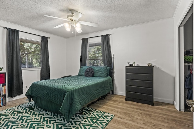 bedroom with ornamental molding, a ceiling fan, a textured ceiling, and wood finished floors