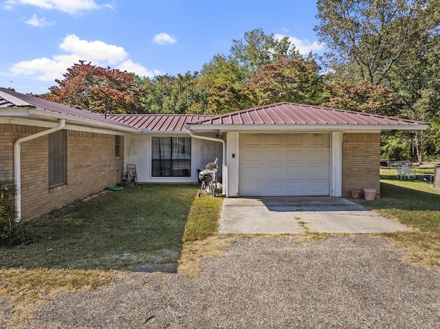 ranch-style house with a garage, metal roof, brick siding, and a front lawn