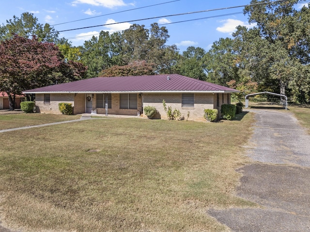 single story home featuring metal roof, brick siding, driveway, a detached carport, and a front lawn