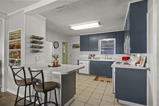 kitchen with blue cabinets, light countertops, white appliances, and visible vents