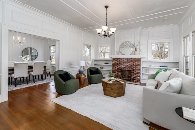 living room with a wealth of natural light, dark wood finished floors, a decorative wall, and a notable chandelier