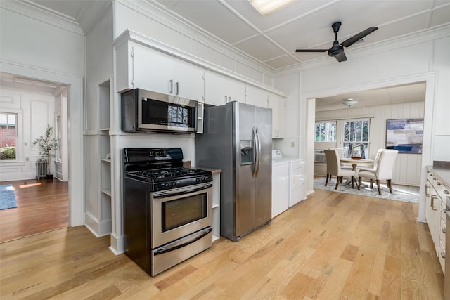 kitchen featuring appliances with stainless steel finishes, light wood-type flooring, washing machine and dryer, and a healthy amount of sunlight