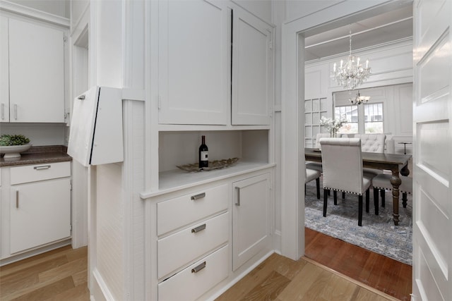 kitchen featuring hanging light fixtures, light wood-style floors, white cabinetry, and a notable chandelier