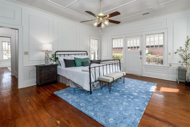 bedroom with access to exterior, wood-type flooring, visible vents, and a decorative wall