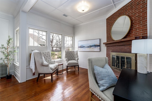 interior space with ornamental molding, hardwood / wood-style flooring, a fireplace, and visible vents