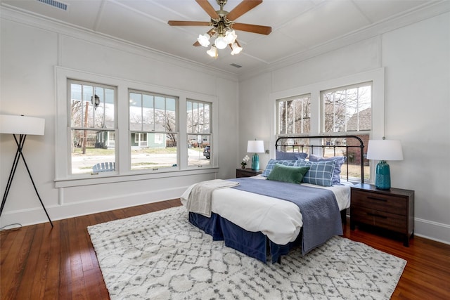 bedroom featuring ornamental molding, multiple windows, and wood finished floors