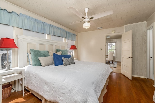 bedroom with ceiling fan, wood finished floors, and visible vents