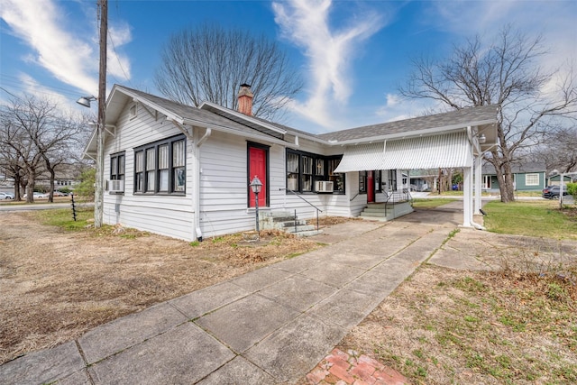 view of front of property featuring a chimney, cooling unit, and roof with shingles