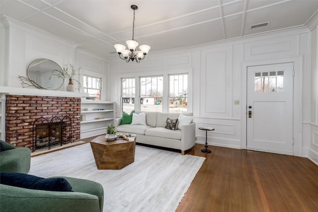 living room with a decorative wall, coffered ceiling, a fireplace, wood finished floors, and visible vents