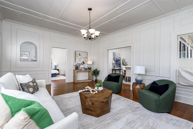 living area featuring a chandelier, visible vents, a decorative wall, and wood finished floors