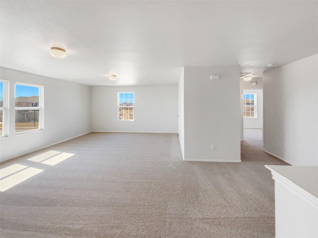 spare room with baseboards and light colored carpet